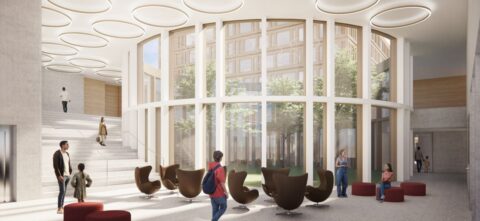 Eine lichtdurchflutete Eingangshalle mit großer Freitreppe, kreisförmigen Deckenleuchten und gemütlichen Sessel-Sitzgruppen vor einer Panorama-Glasfront.