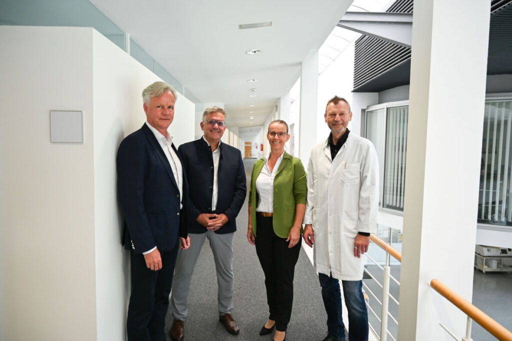 Pflegedirektorin DGKP Martina Baumgartl, MSc. steht gemeinsam mit Geschäftsführer, Dir. Dr. Gerald Fleisch und Dir. Priv.-Doz. Dr. Peter Fraunberger, und Mag. Dr. Andreas Stieger (Leitung Personalmanagement) in einem hellen Flur des Krankenhauses.