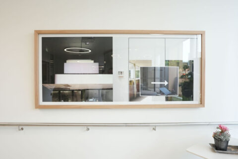 Ein großes gerahmtes Bild mit Architekturfotografien hängt an einer weißen Wand im Korridor.