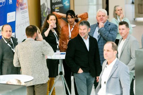 Eine Gruppe von Veranstaltungsgästen steht entspannt zwischen den Ausstellungsständen und unterhält sich.