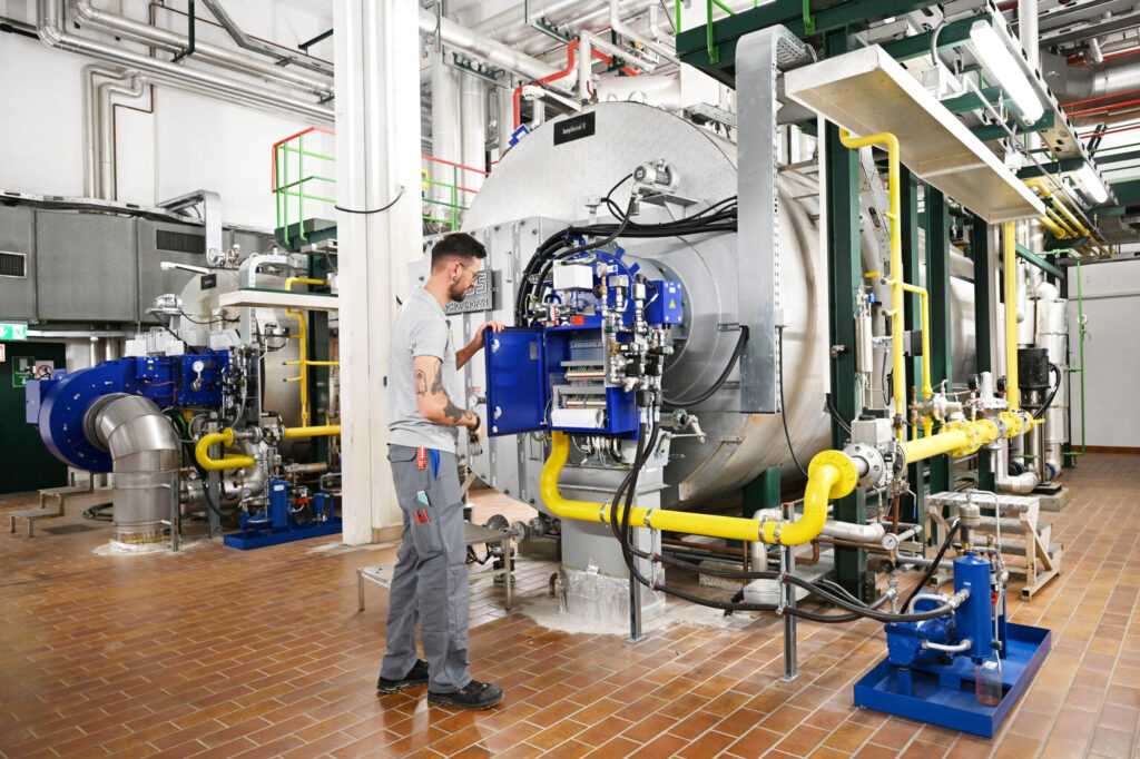 Ein Haustechniker überprüft die Steuereinheit eines Industriekessels.